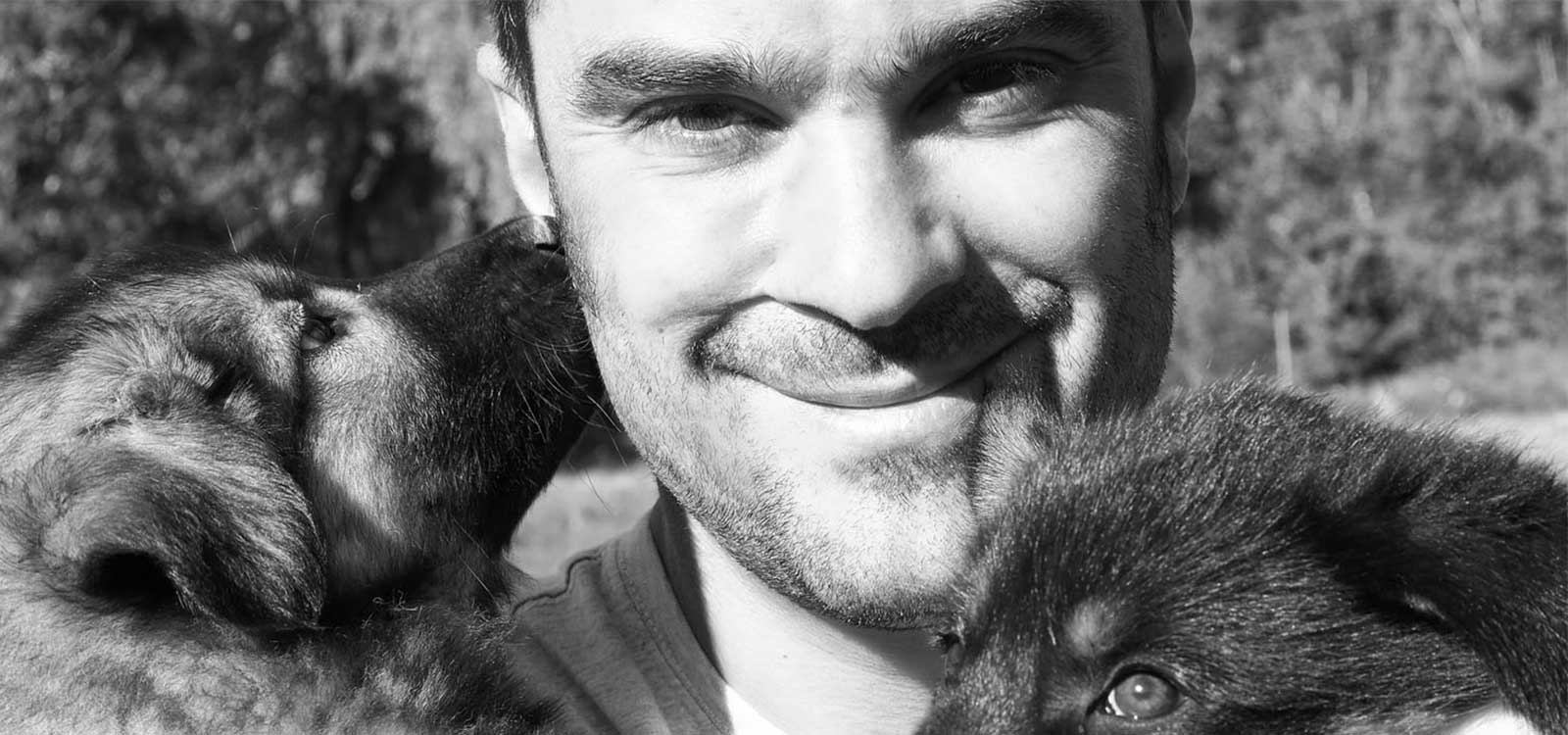 Portrait de Benoit Verin votre musher professionnel entouré de deux chiots.