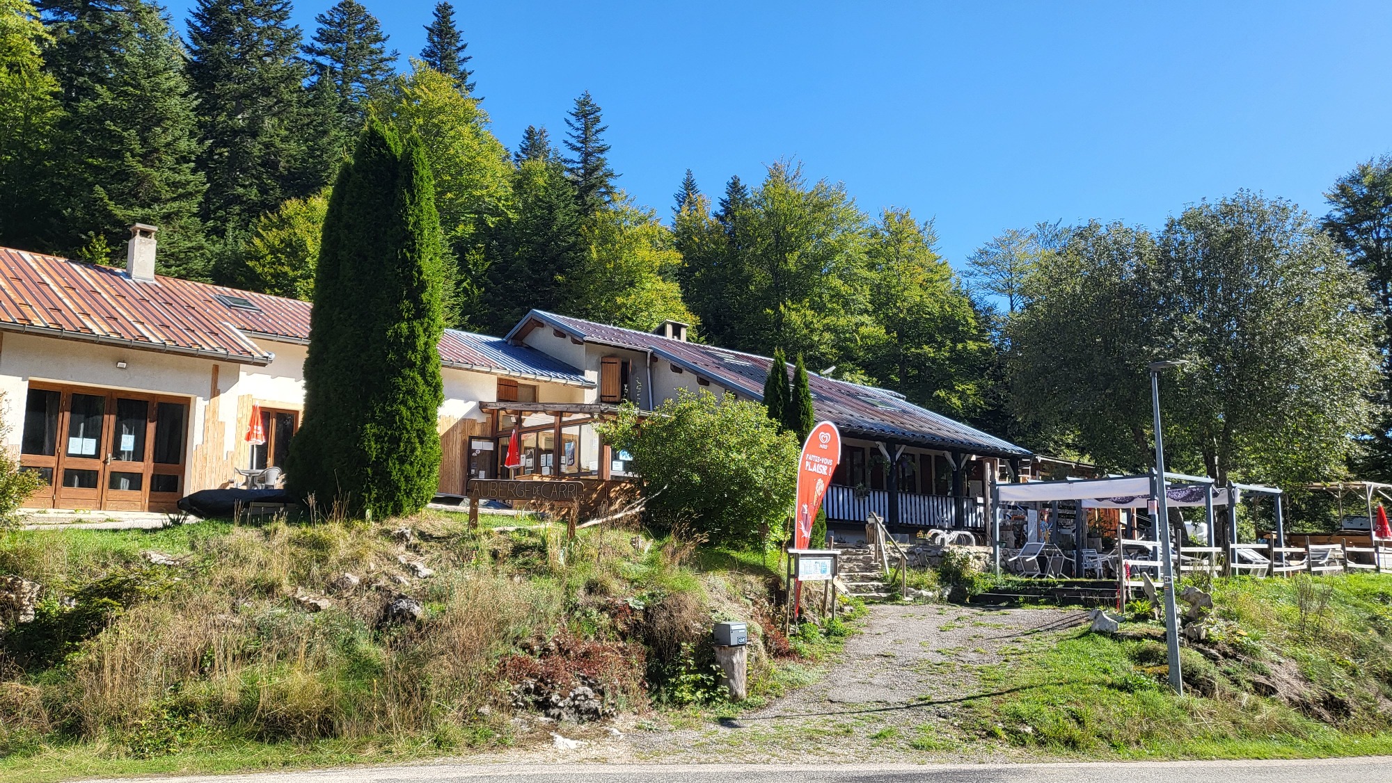 L’auberge, prolongée d’une terrasse couverte aménagée de tables et de chaises, est attenante à l’espace locatif de matériel de sports d’hiver. L’ensemble baigne dans une atmosphère lumineuse et ensoleillée