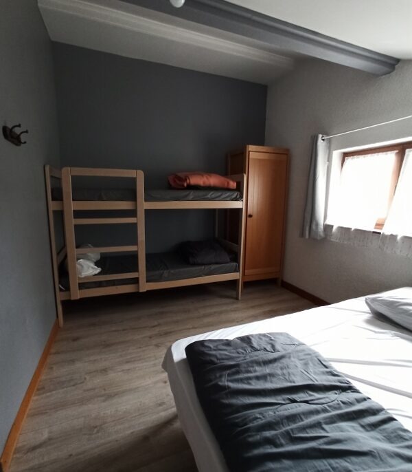 La chambre thalia du Gîte et auberge de Carri à La Chapelle en Vercors. Une chambre sobre et lumineuse, avec literie confortable, une étagère en bois et une fenêtre laissant entrer la lumière naturelle.
